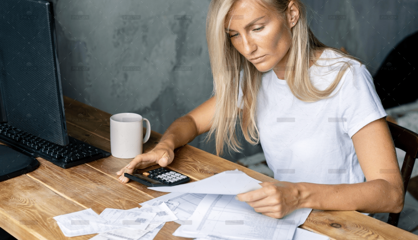 A woman sitting at a table with papers and a calculator.